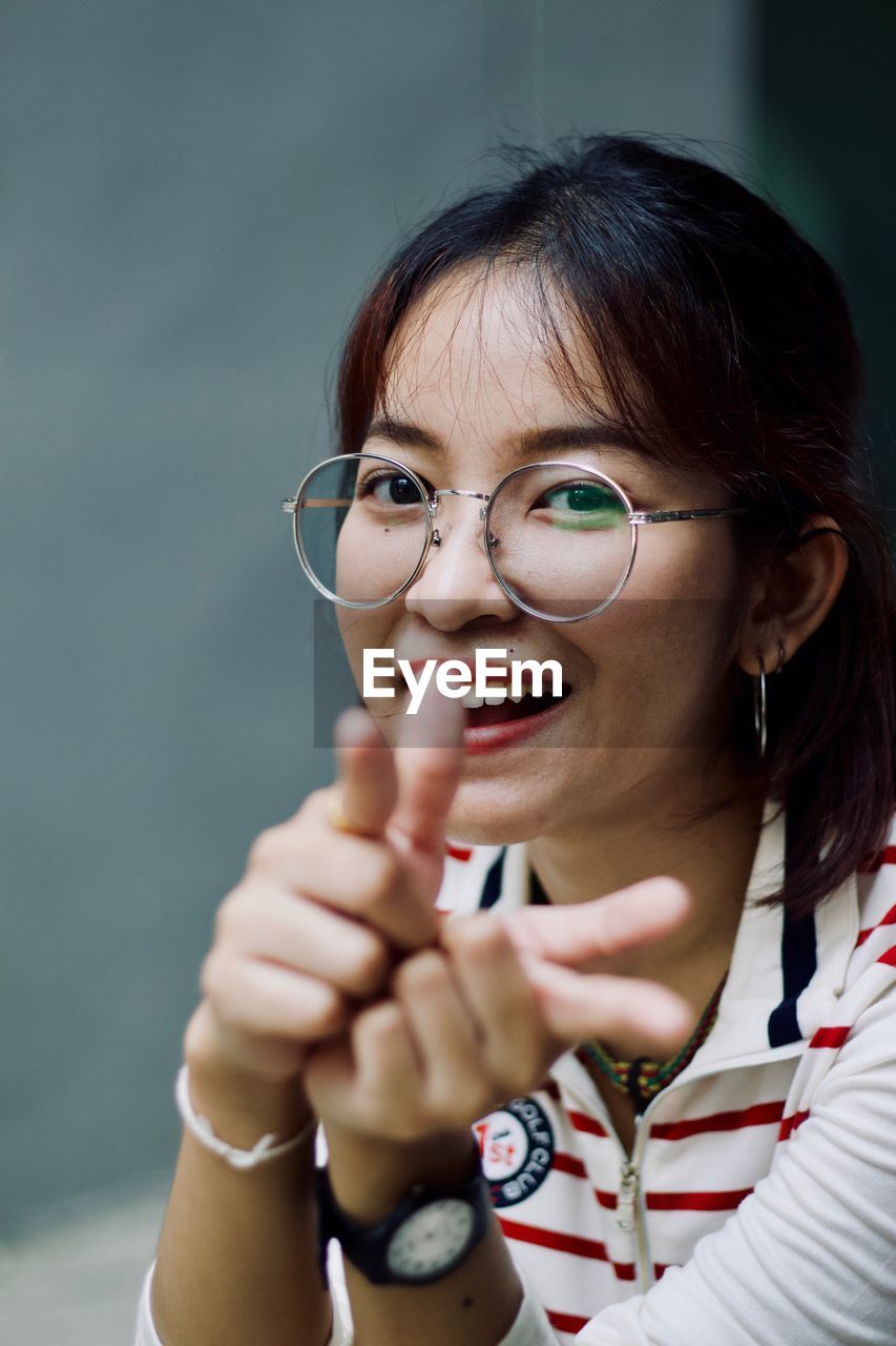 PORTRAIT OF A SMILING YOUNG WOMAN WITH EYEGLASSES