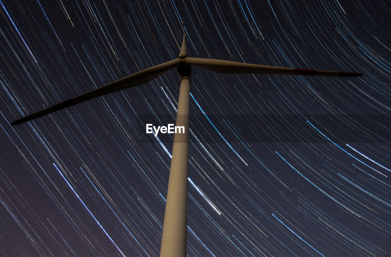 Low angle view of windmill against star field at night