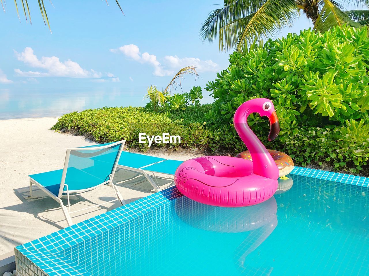 View of pink inflatable  flamingo in swimming pool by  sea side. 