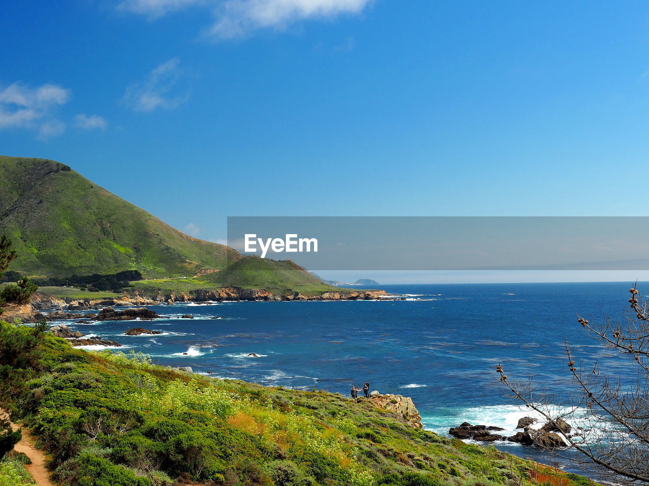 Scenic view of mountains by sea against blue sky