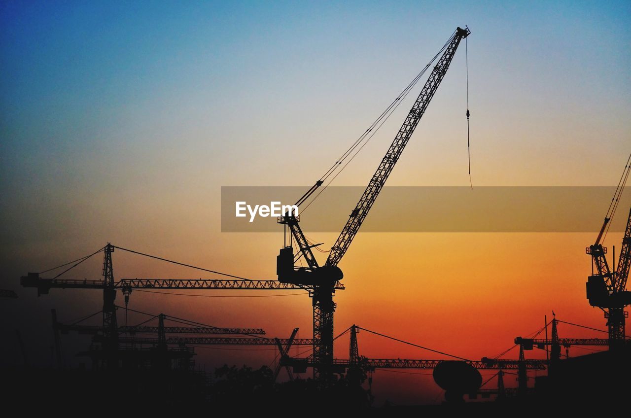 Silhouette of cranes against dramatic sky