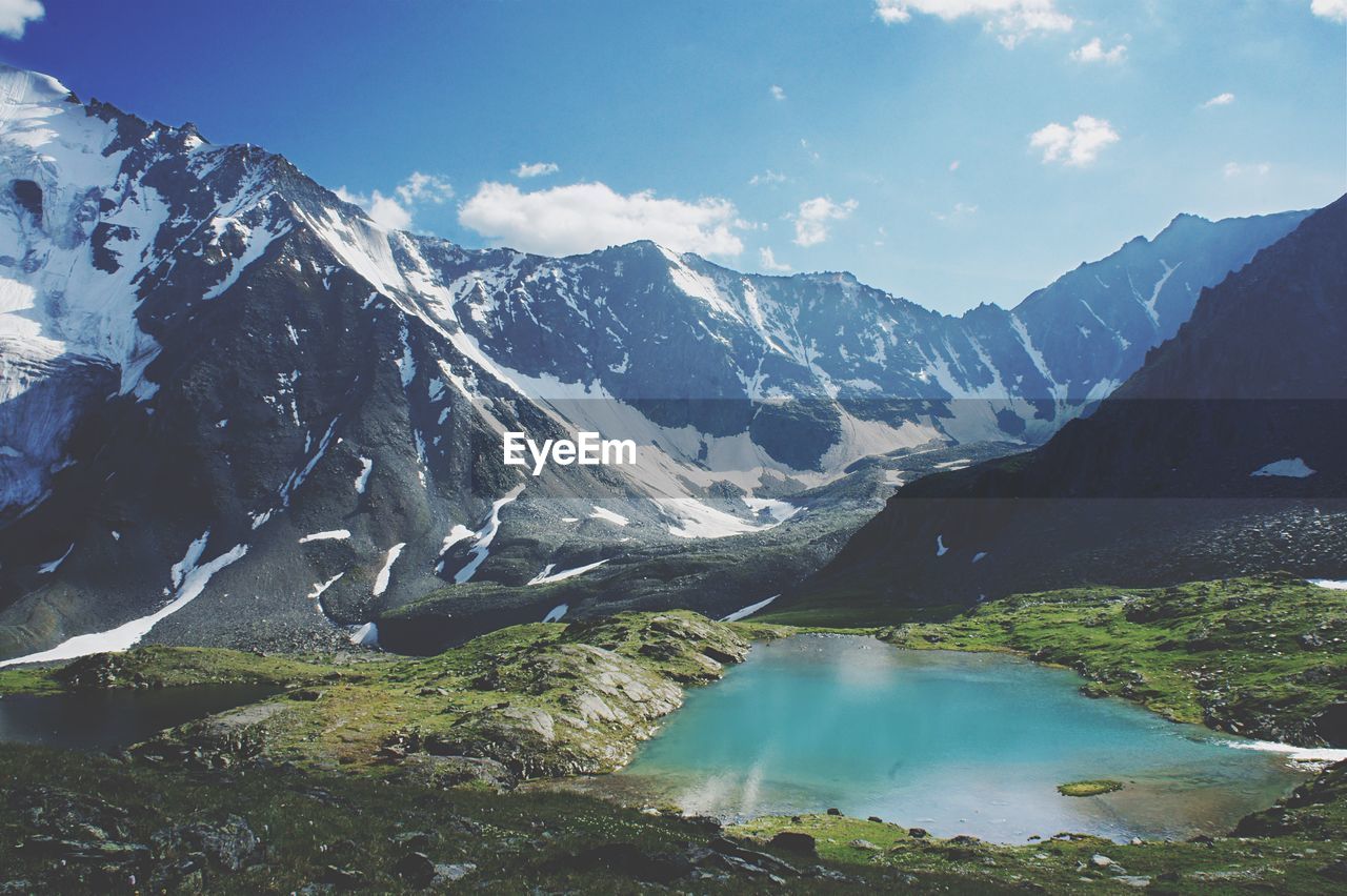 Scenic view of lake amidst mountains against sky during sunny day