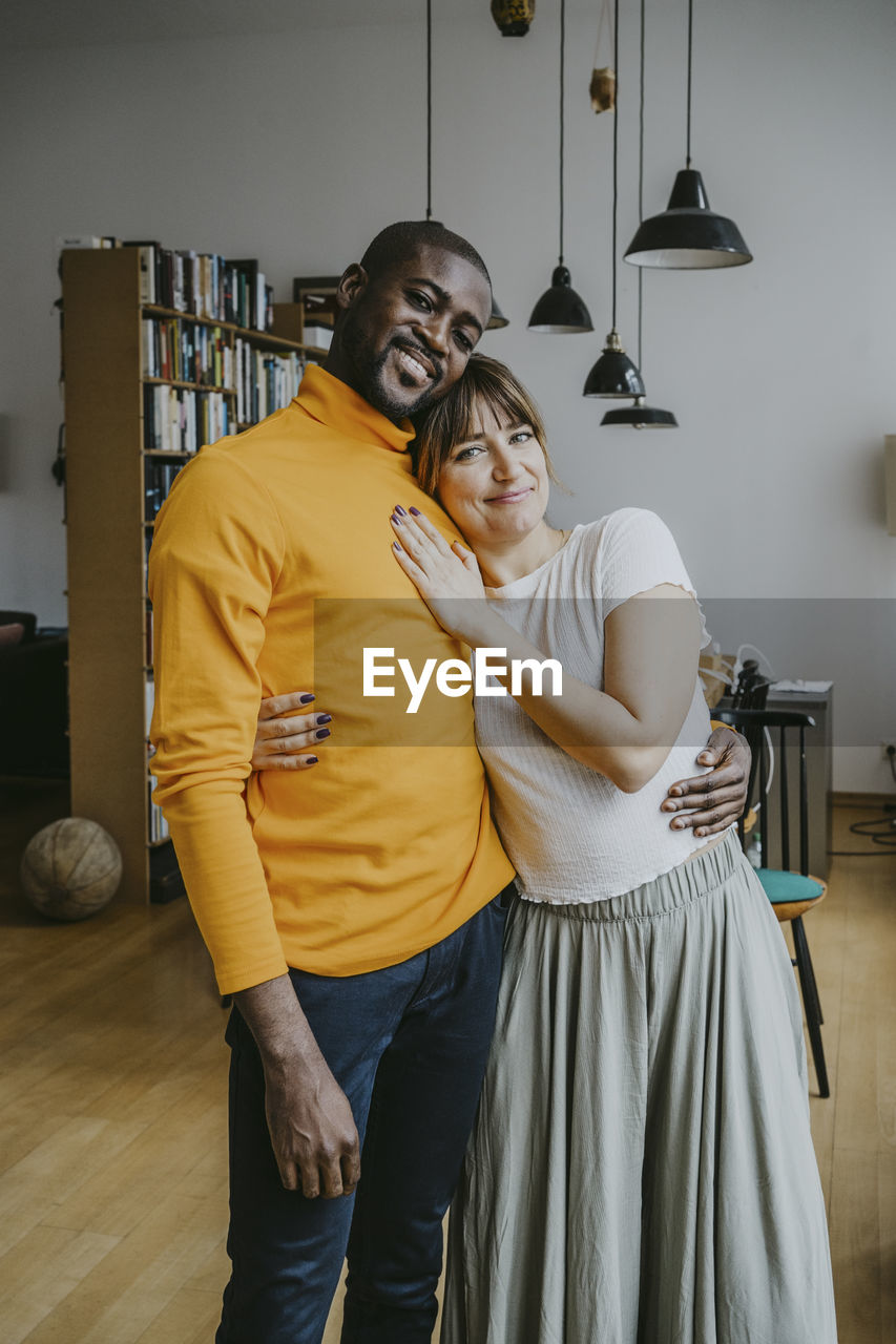 Portrait of smiling couple standing with arm around at home