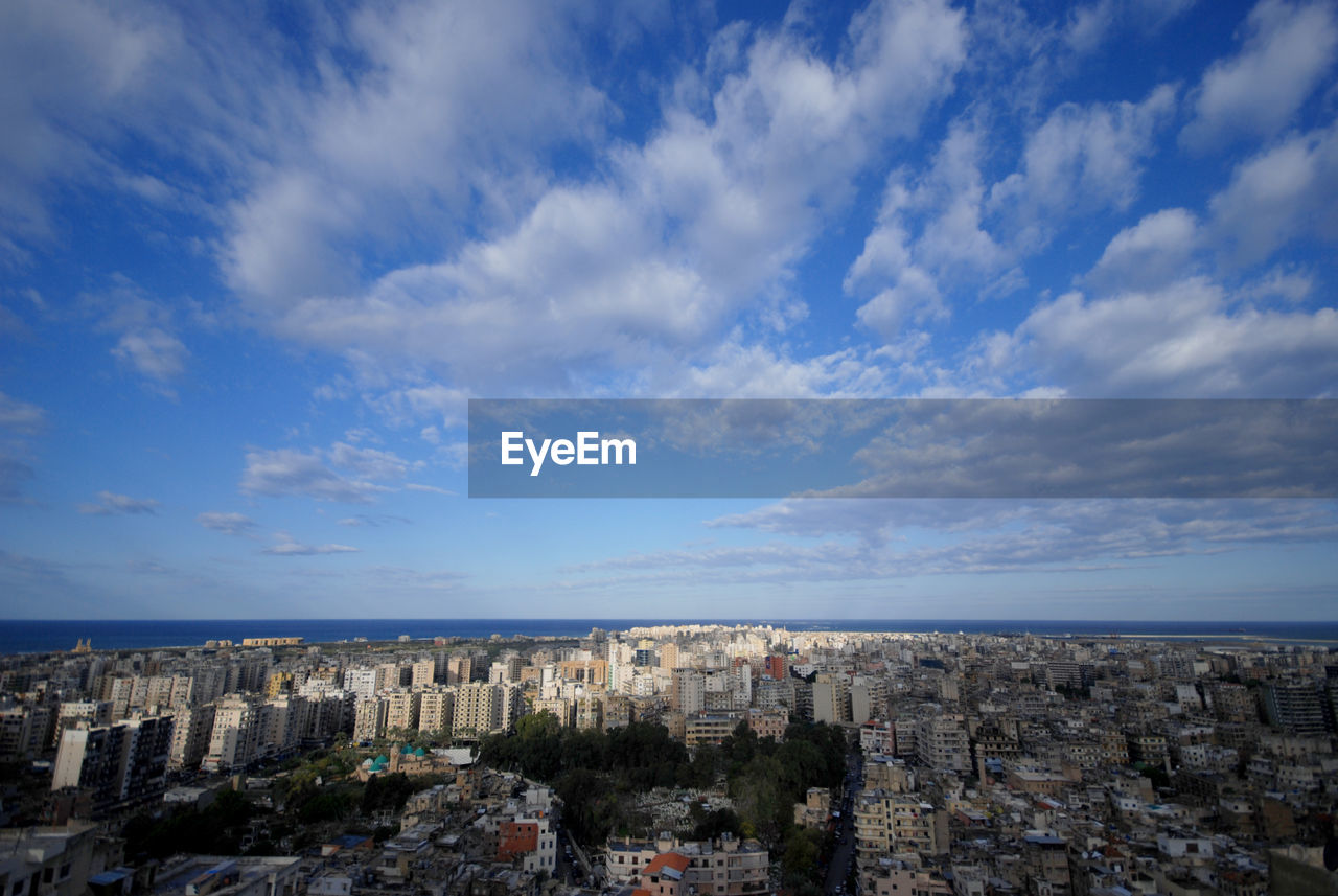 Aerial view of cityscape by sea against sky