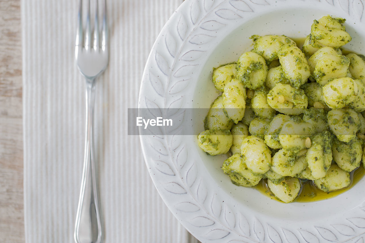 A plate with gnocchi with basil pesto and a fork.