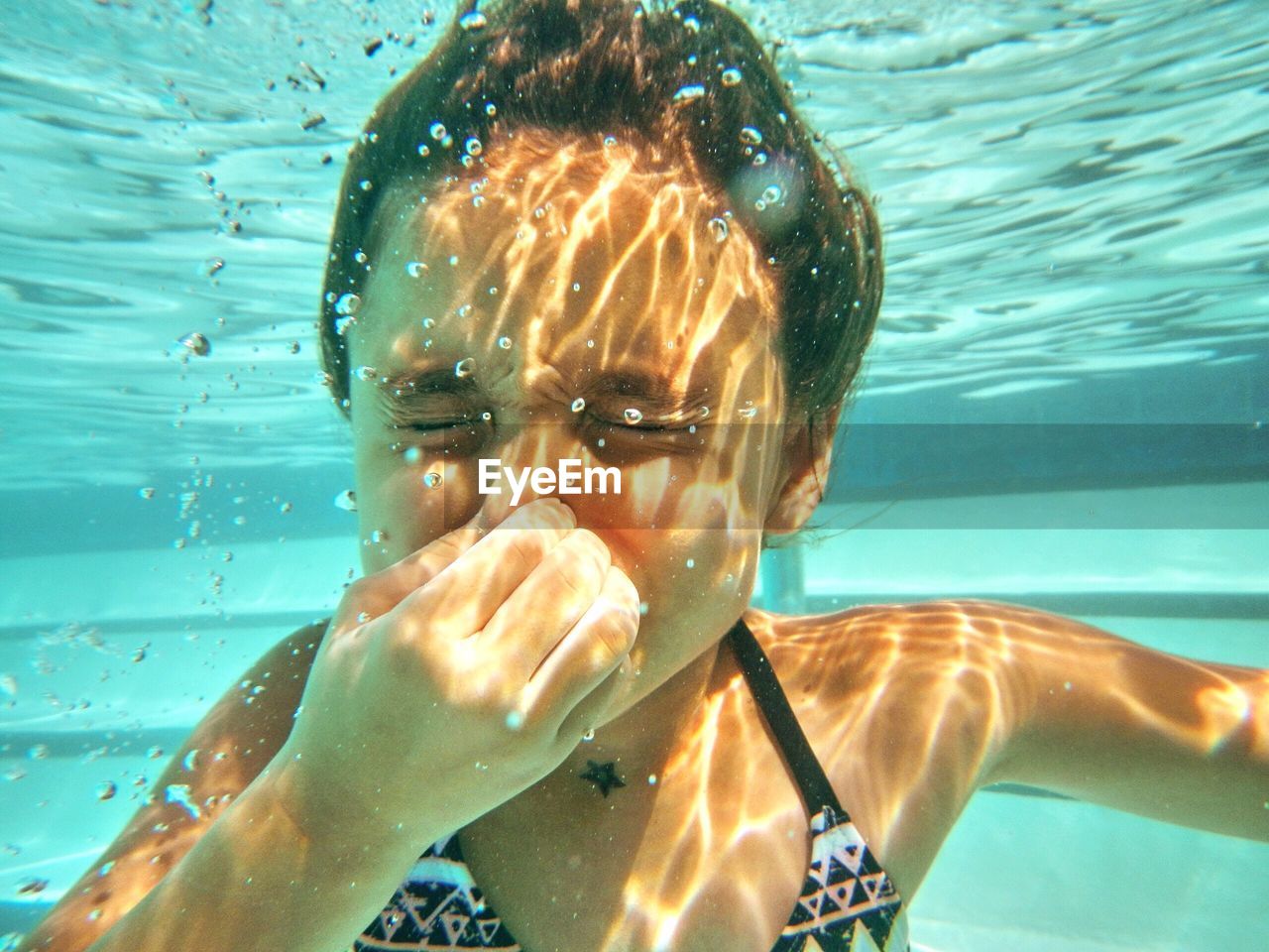 Cute girl holding breath underwater in swimming pool