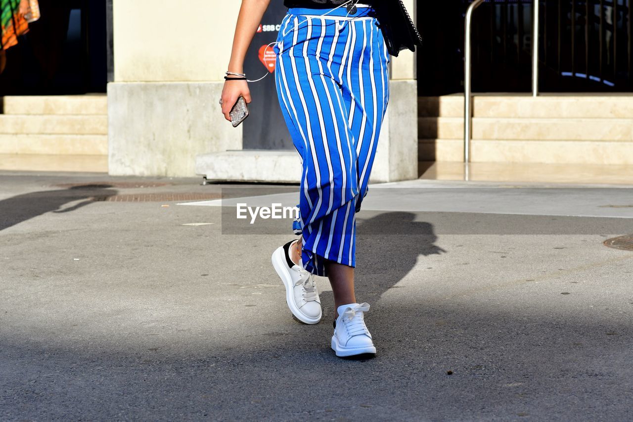 LOW SECTION OF WOMAN WALKING IN STREET