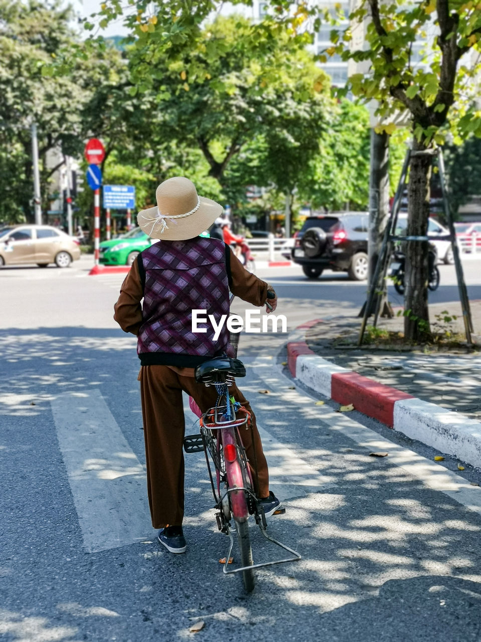 REAR VIEW OF PERSON RIDING BICYCLE ON STREET