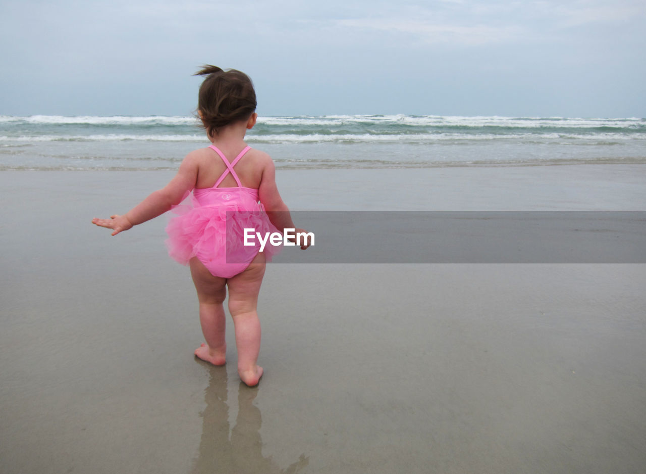 Rear view of baby girl walking on sea shore