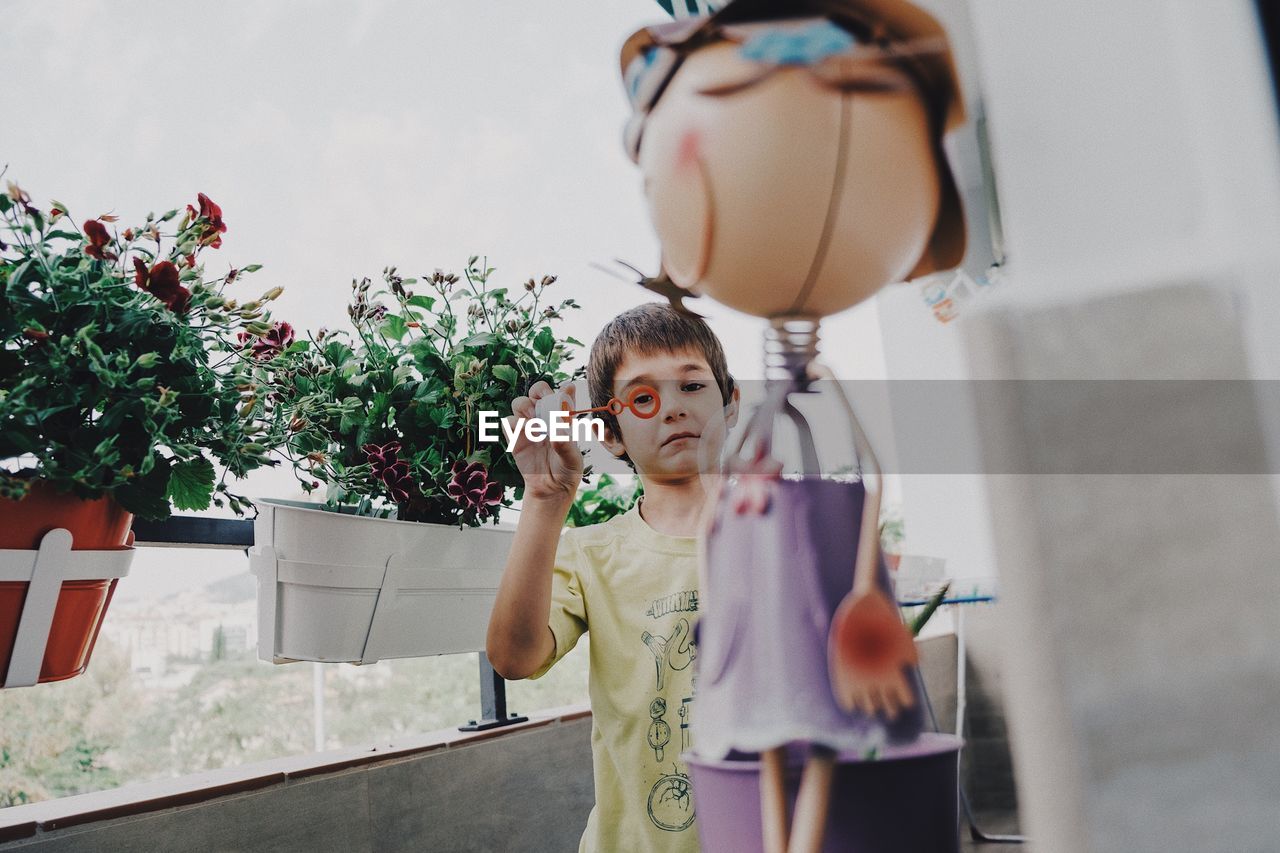 Portrait of boy looking through bubble wand in balcony