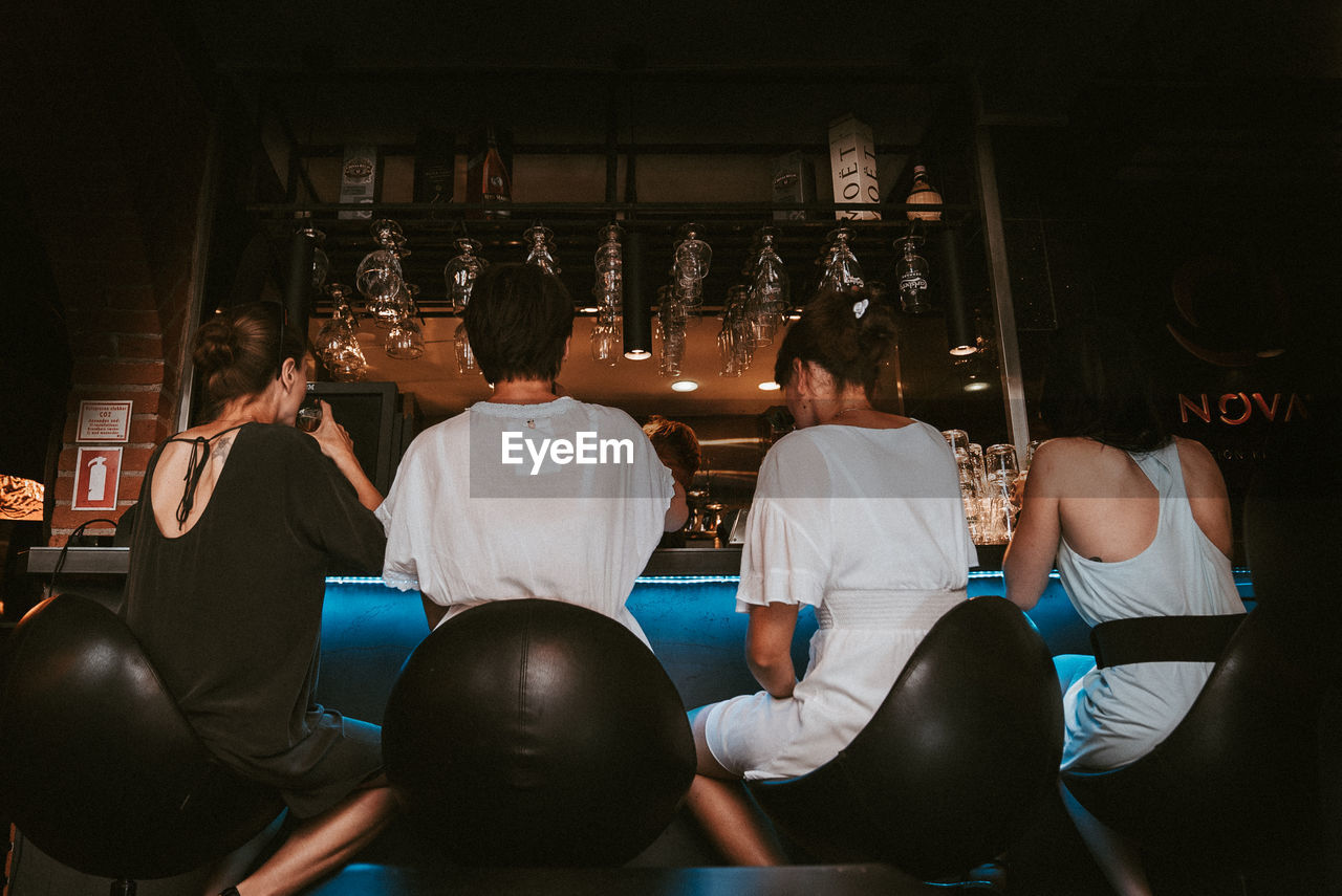 REAR VIEW OF PEOPLE SITTING IN THE ROOM