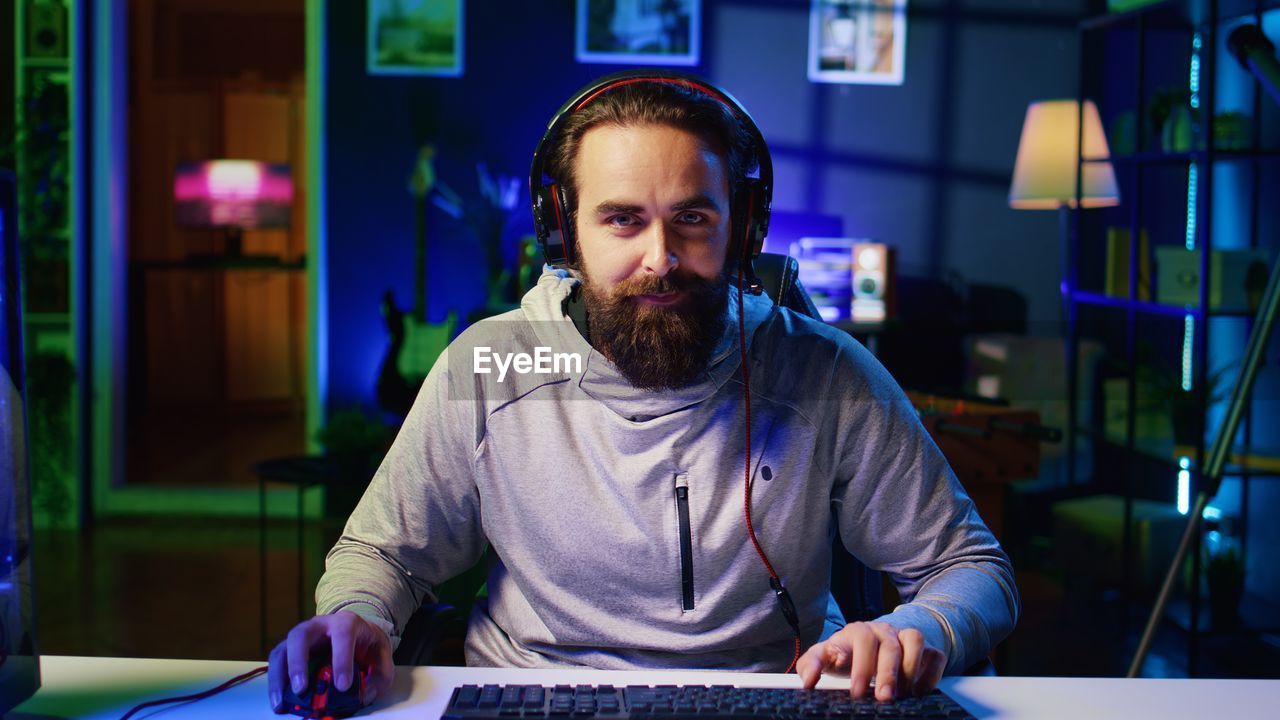 portrait of young man using mobile phone while sitting at home