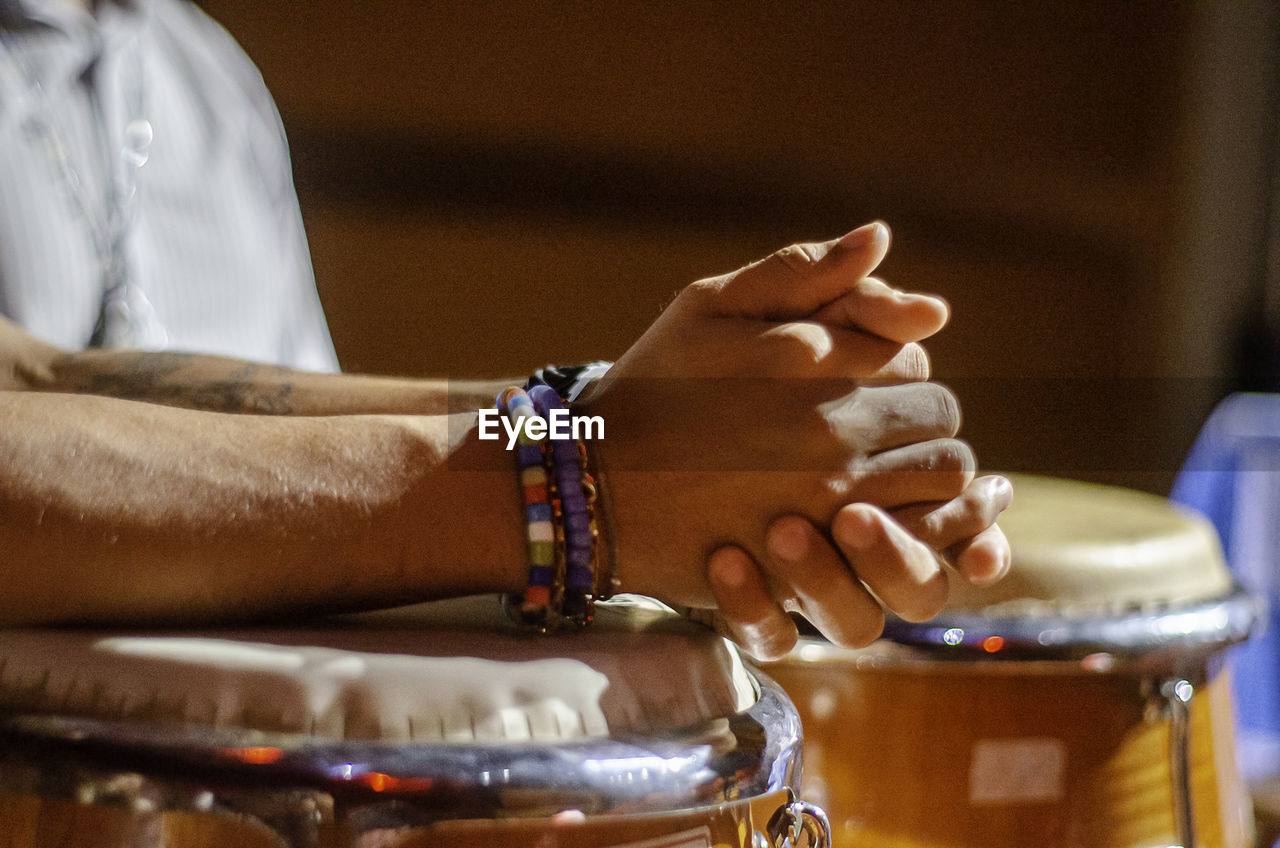 drum, membranophone, hand, hand drum, one person, percussion, musical instrument, adult, arts culture and entertainment, drum - percussion instrument, musical equipment, music, indoors, close-up, bracelet, midsection