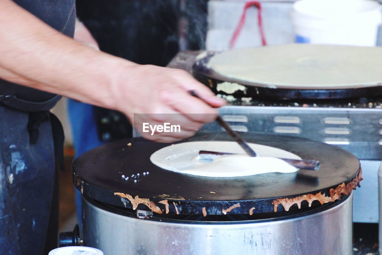 Cropped image of man preparing thosai on stove