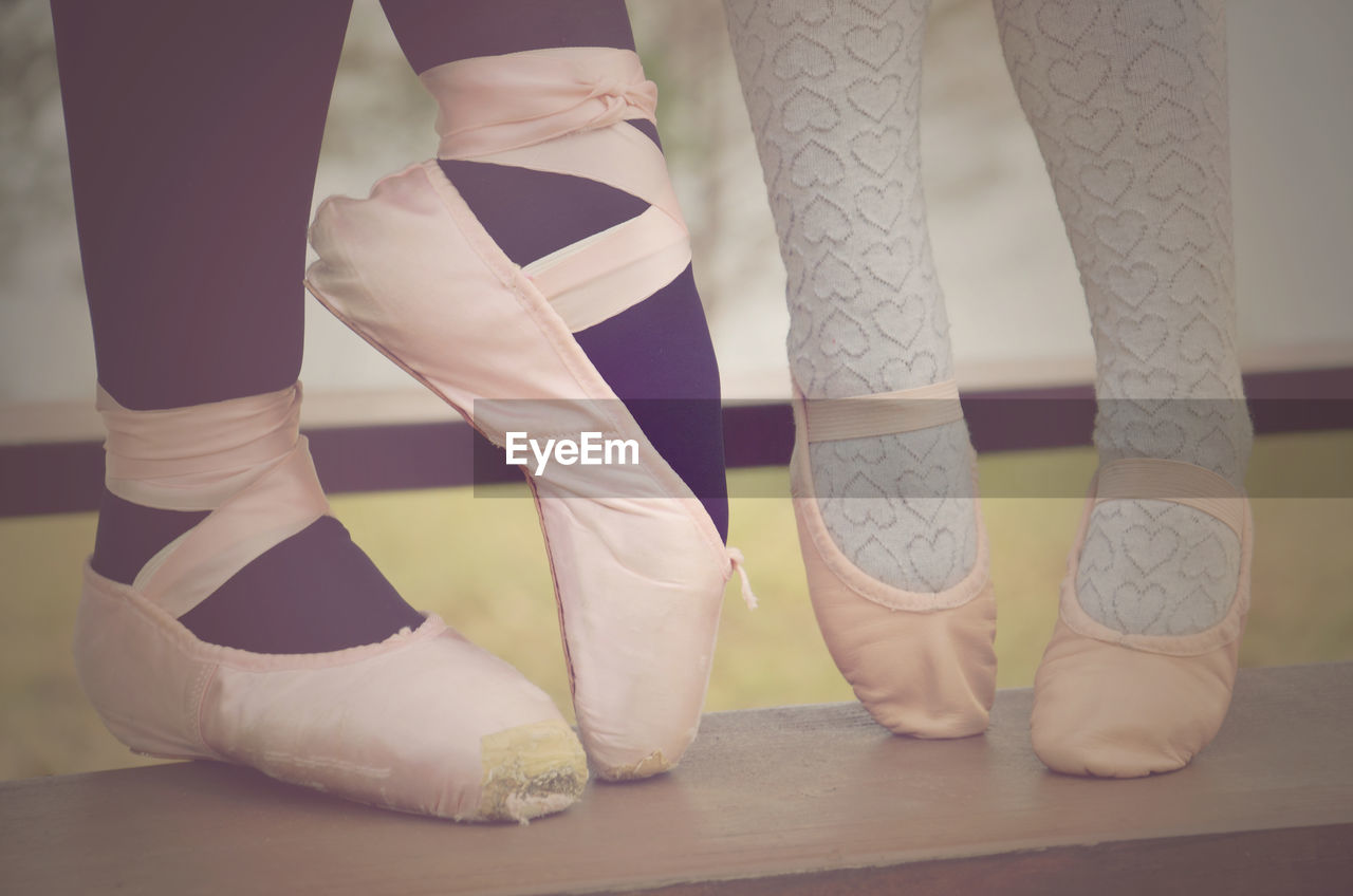 Low section of woman and girl wearing ballet shoes