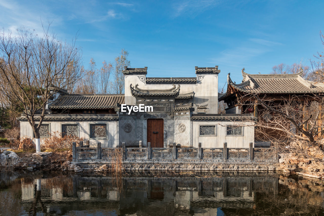 Hui-style architecture by lake against sky