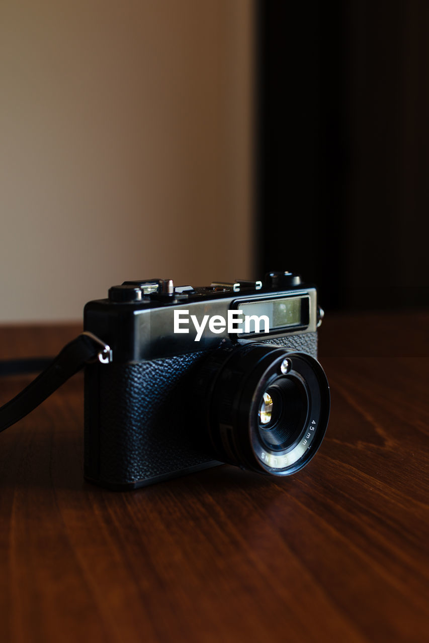 Side view of vintage photo camera on a wooden table