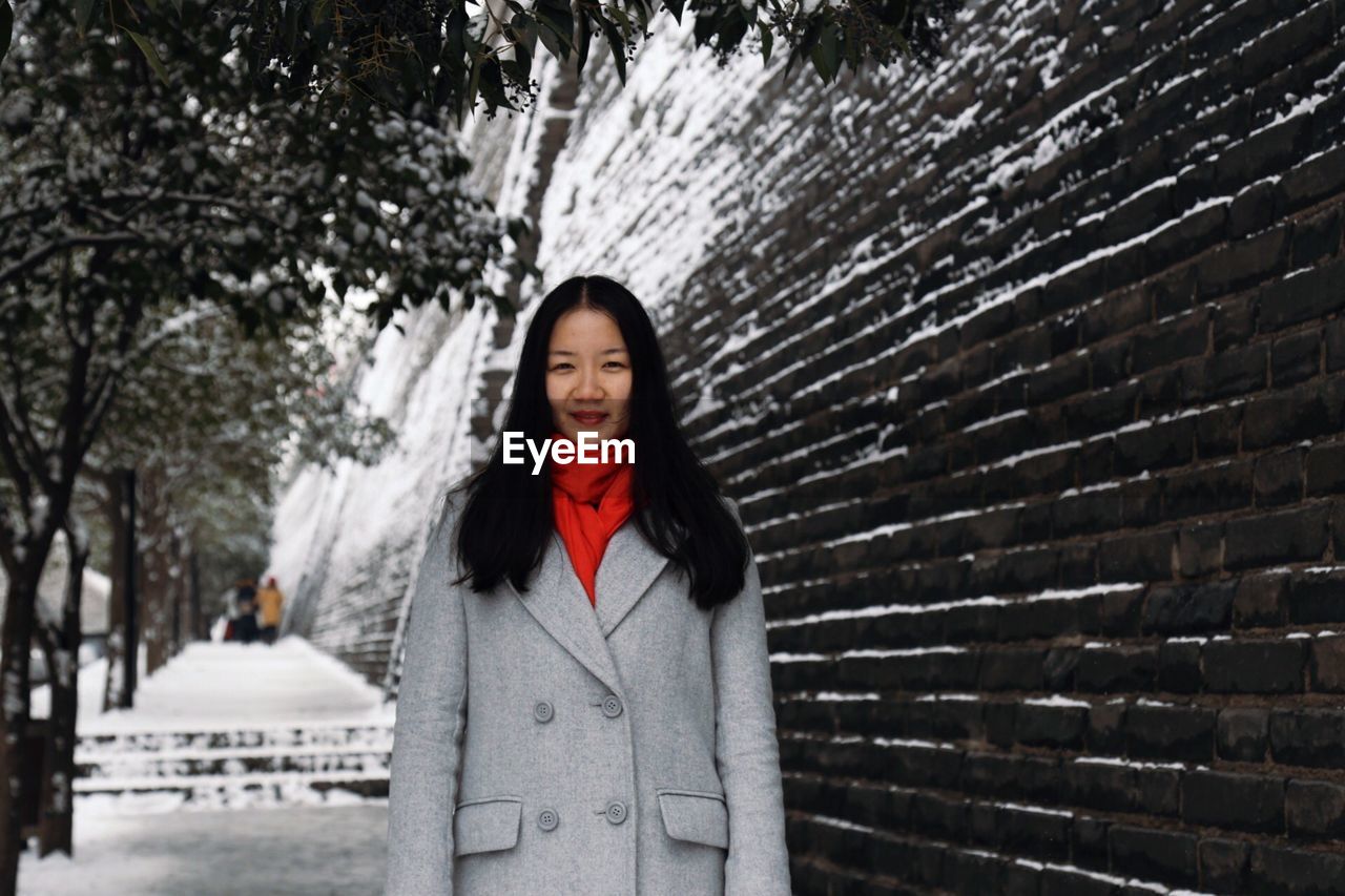 Portrait young woman against wall during winter