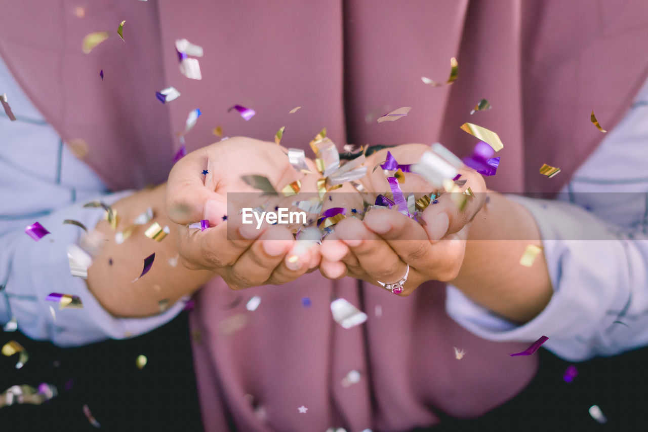 Midsection of woman holding confetti