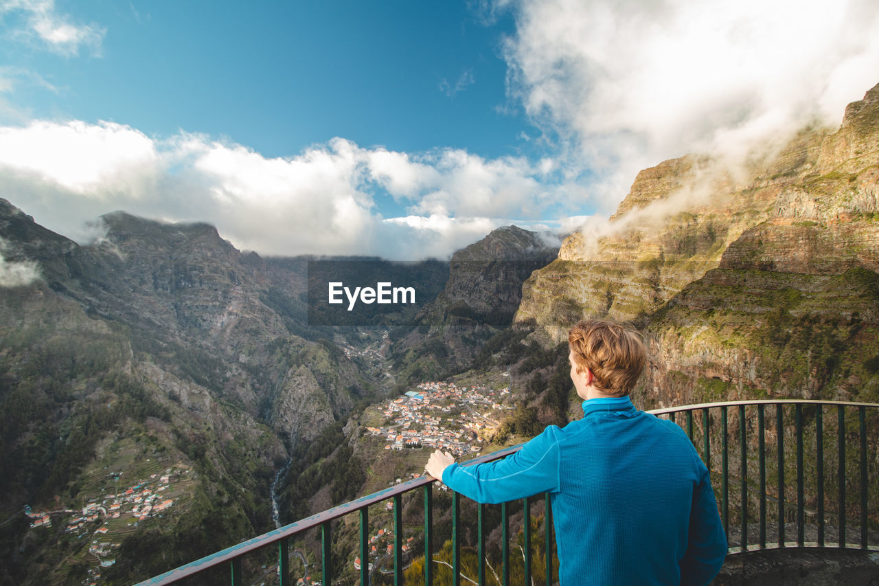 Blonde man looks out over the village of curral das freiras on the island of madeira, portugal