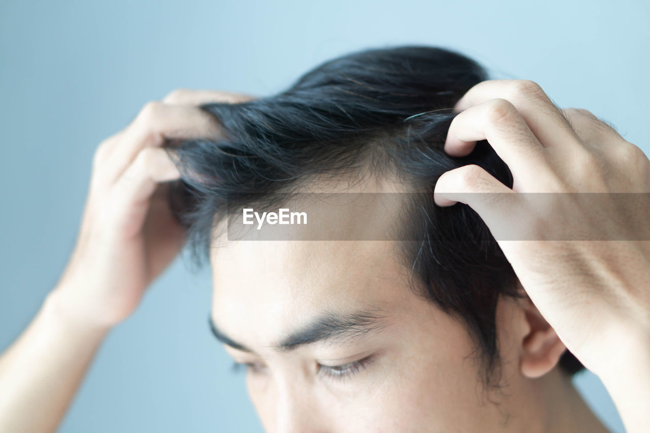 Close-up of man touching his hair at home