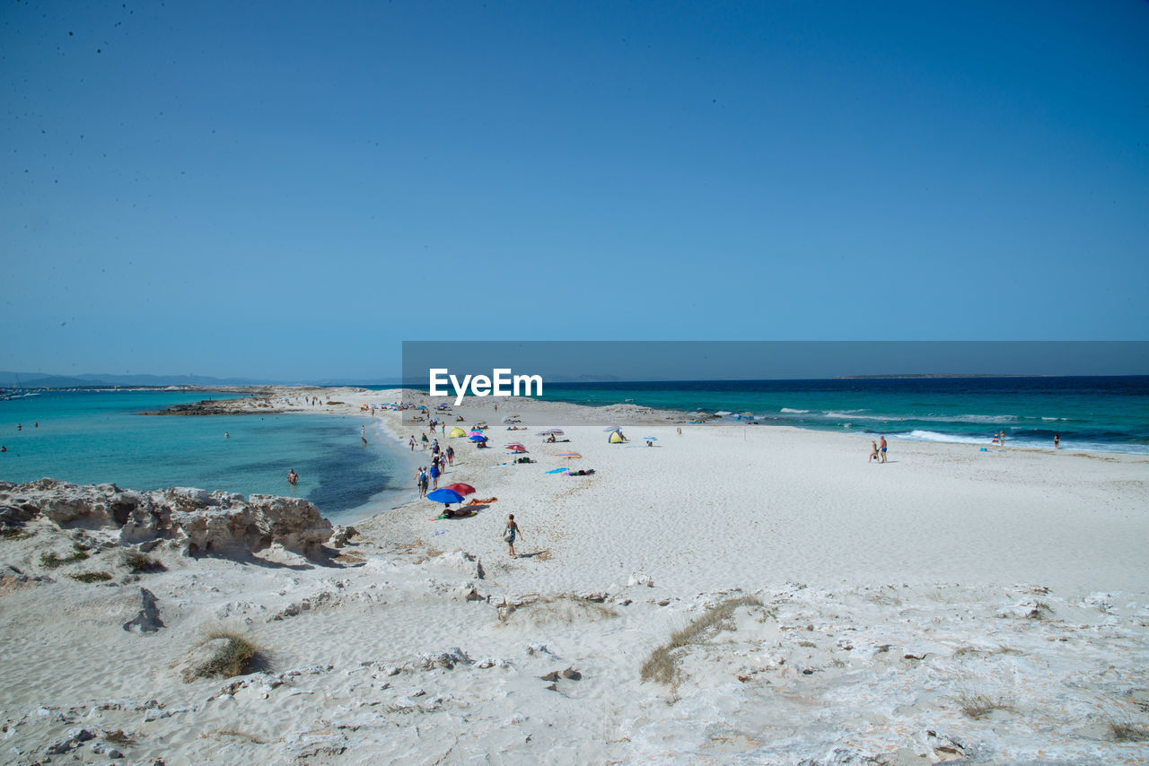 People at beach against clear sky