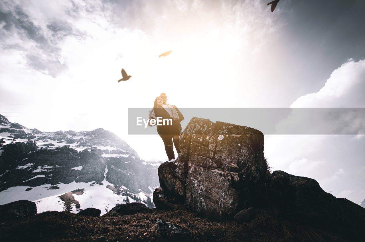 MAN ON ROCKS AGAINST MOUNTAIN