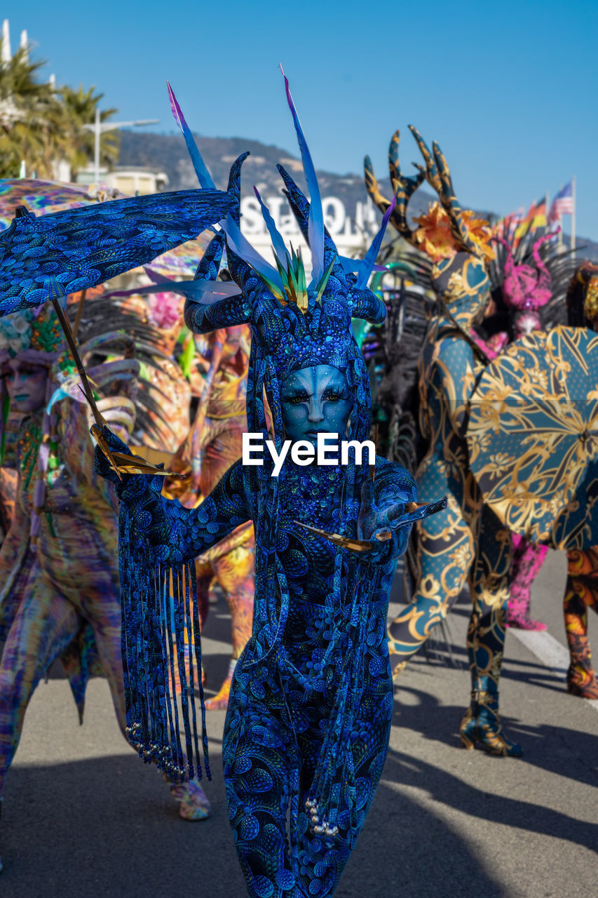 carnival, tradition, festival, multi colored, blue, celebration, day, nature, sky, outdoors, clothing, transportation, city, arts culture and entertainment, travel destinations, sunlight, street, person, mask - disguise