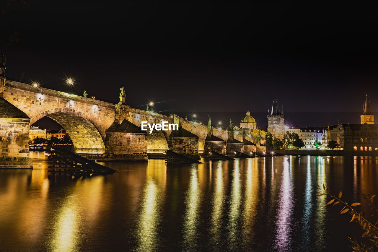 Illuminated bridge over river at night