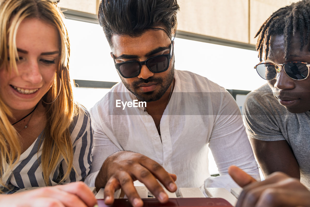 Small group of multiethnic friends having fun surfing the net on laptop - summer vacation concept