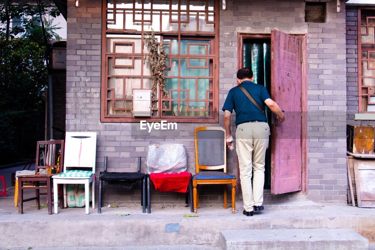 Rear view of man opening door of house