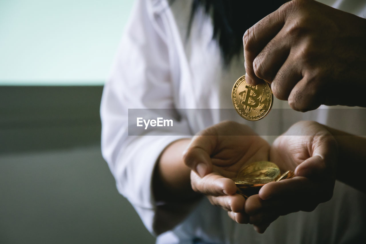 Cropped image of man giving coin to woman