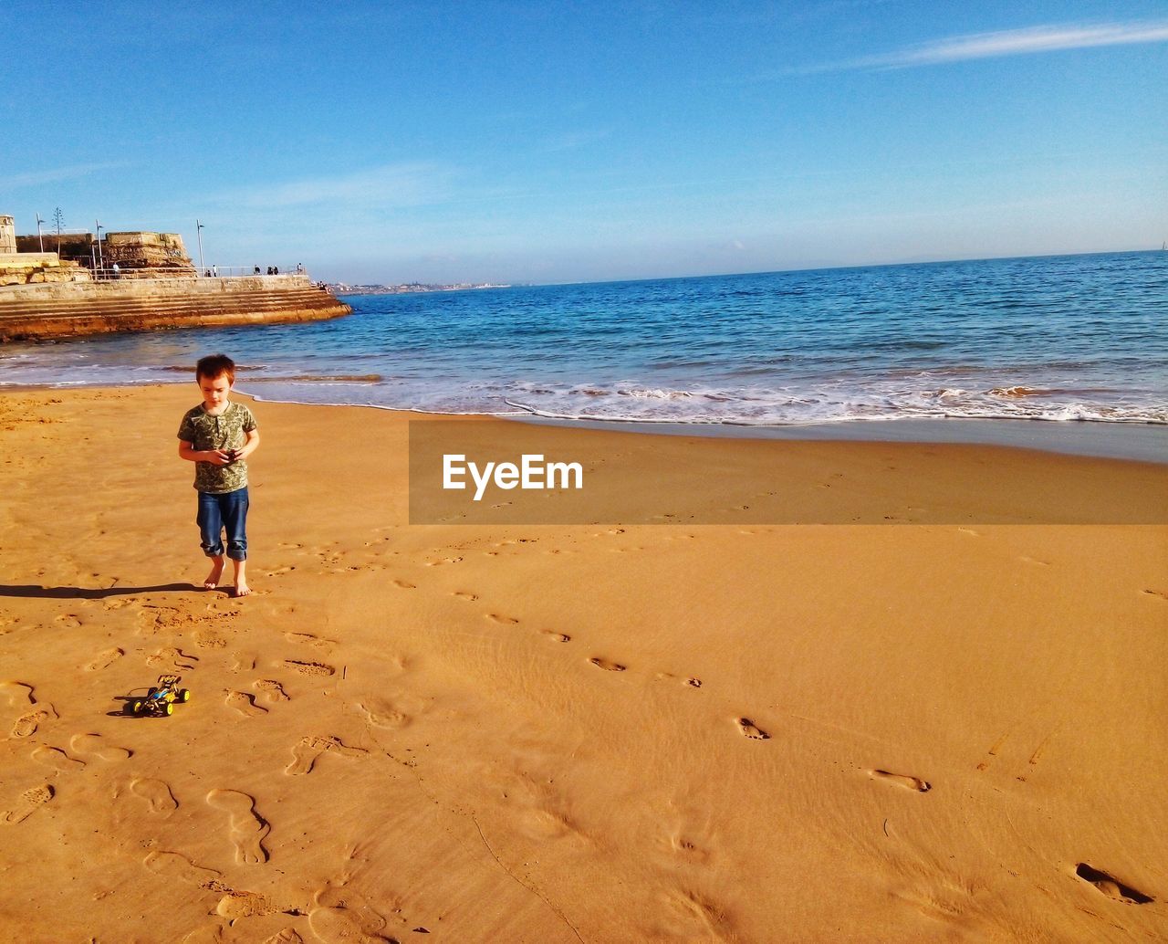 Boy walking at beach against sky