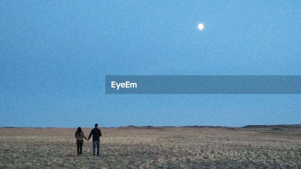 MEN STANDING ON FIELD AGAINST SKY