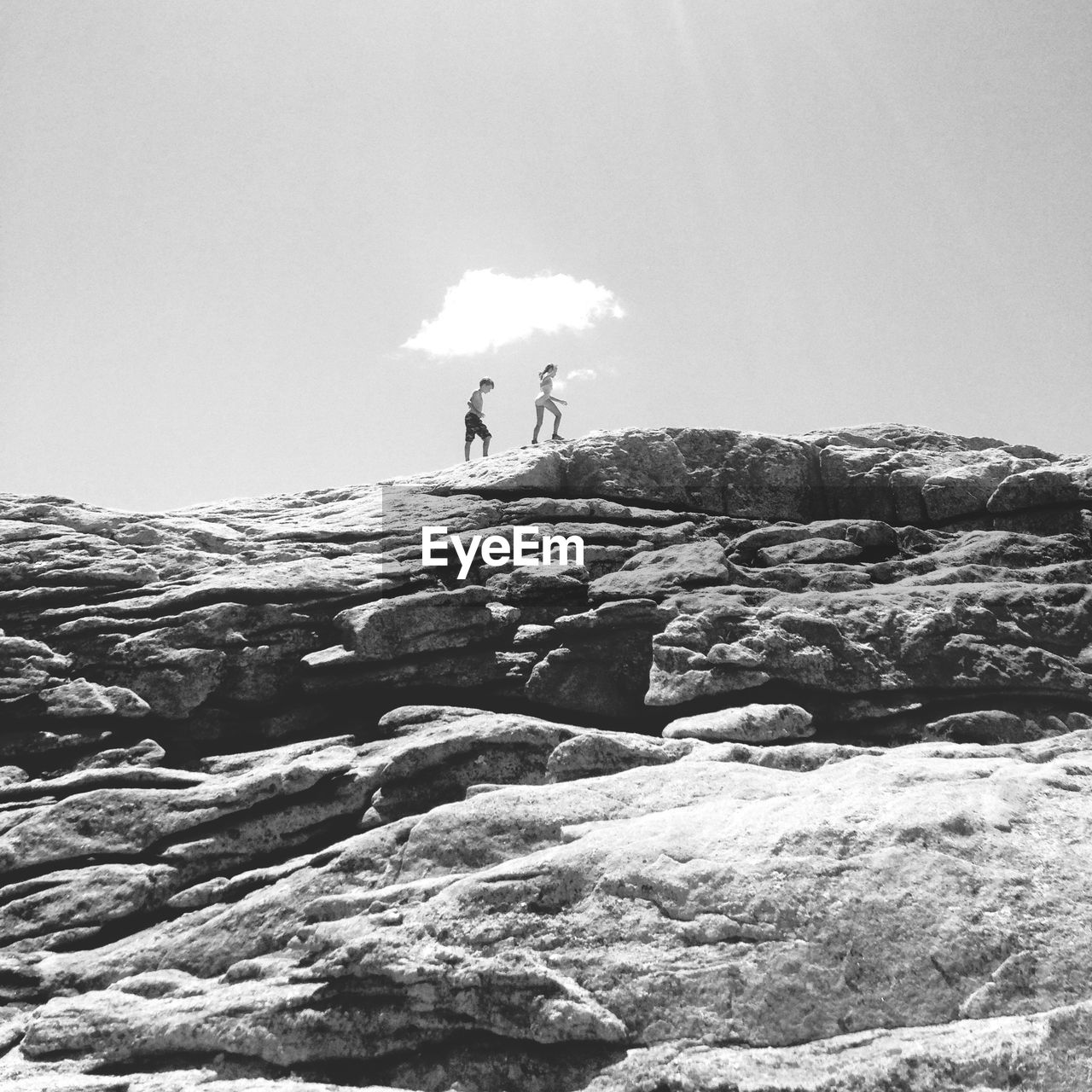 Low angle view of siblings walking on cliff