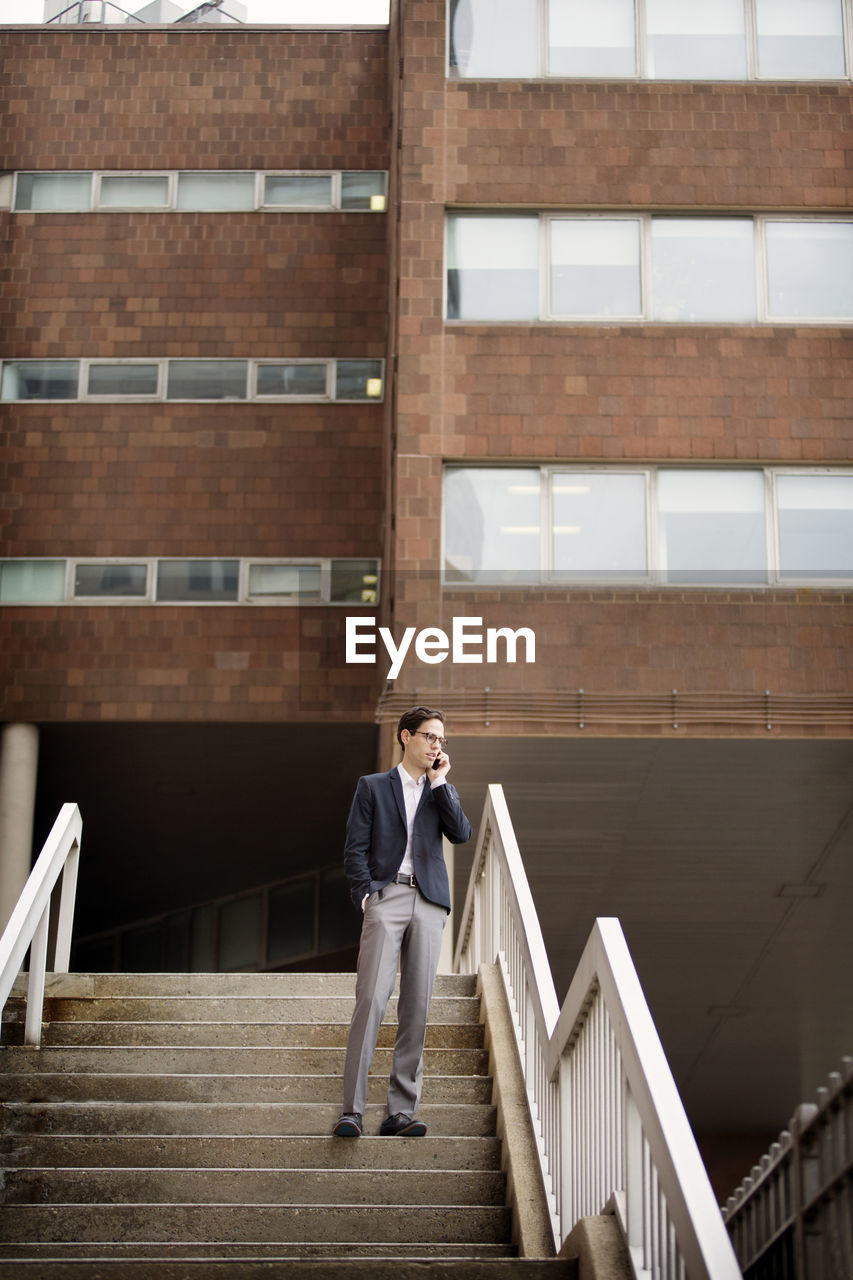 Businessman talking on mobile phone while standing on steps