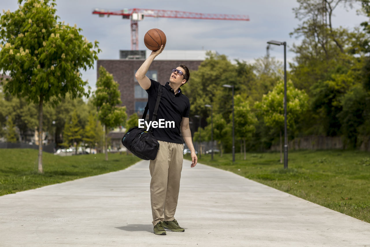 Close-up of mature man throwing basketball while standing outdoors