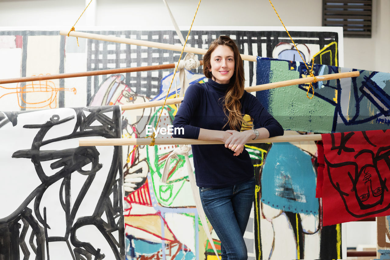 Portrait of confident female artist standing in art studio