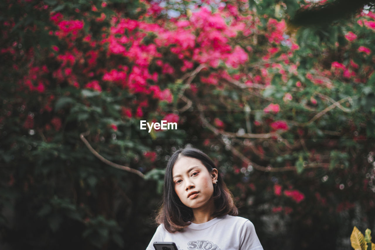 Portrait of young woman against tree