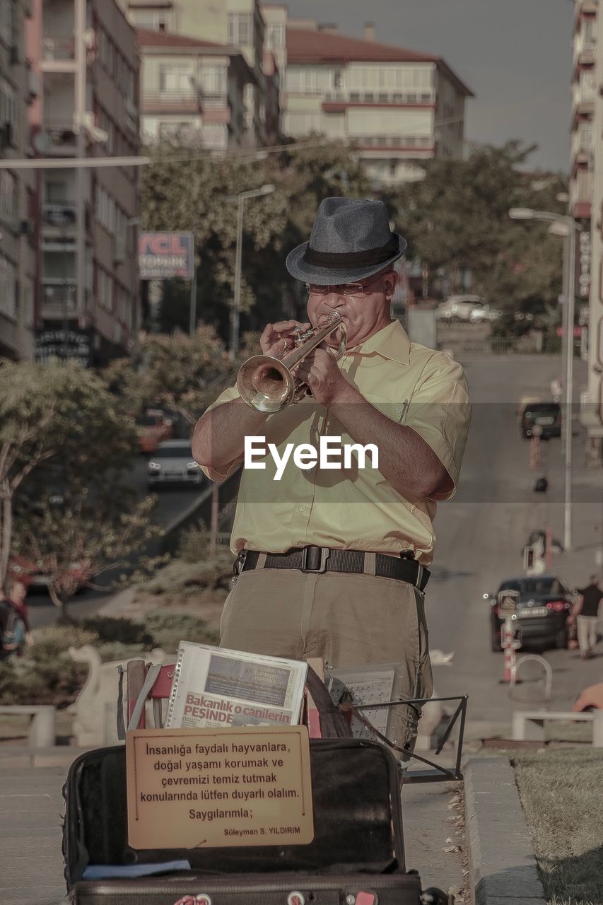 Senior man playing trumpet while standing on street