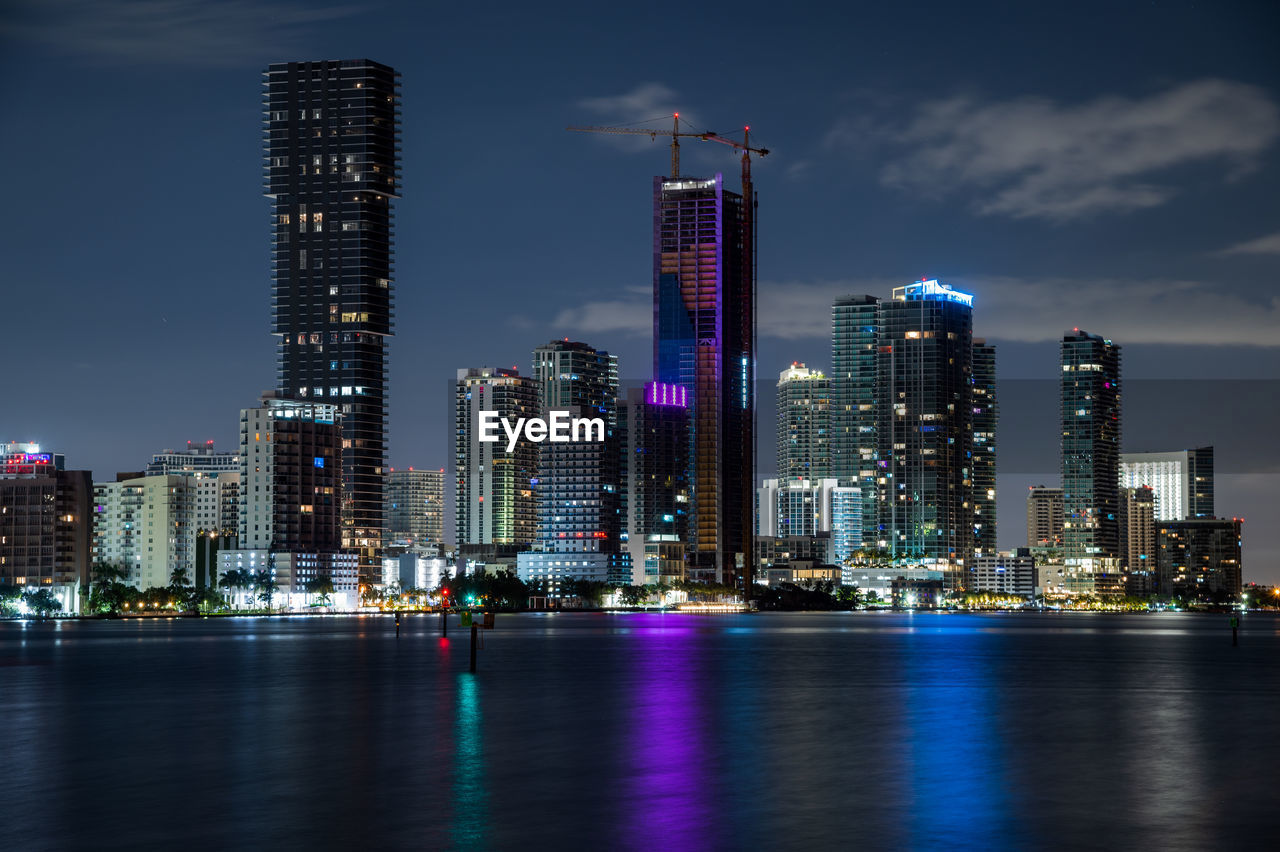 architecture, city, building exterior, built structure, office building exterior, skyscraper, skyline, building, landscape, metropolitan area, urban skyline, illuminated, cityscape, night, horizon, sky, metropolis, residential district, water, downtown district, travel destinations, reflection, office, dusk, urban area, city life, nature, tower block, waterfront, downtown, no people, landmark, business, tower, travel, outdoors, financial district, development, evening, long exposure, river, business finance and industry, transportation, street, cloud, lighting equipment
