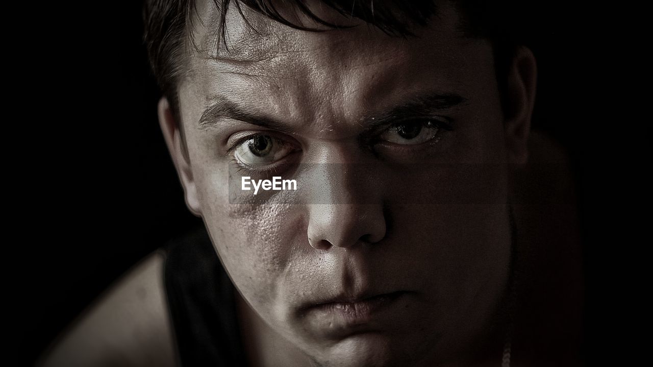 Portrait of angry man against black background