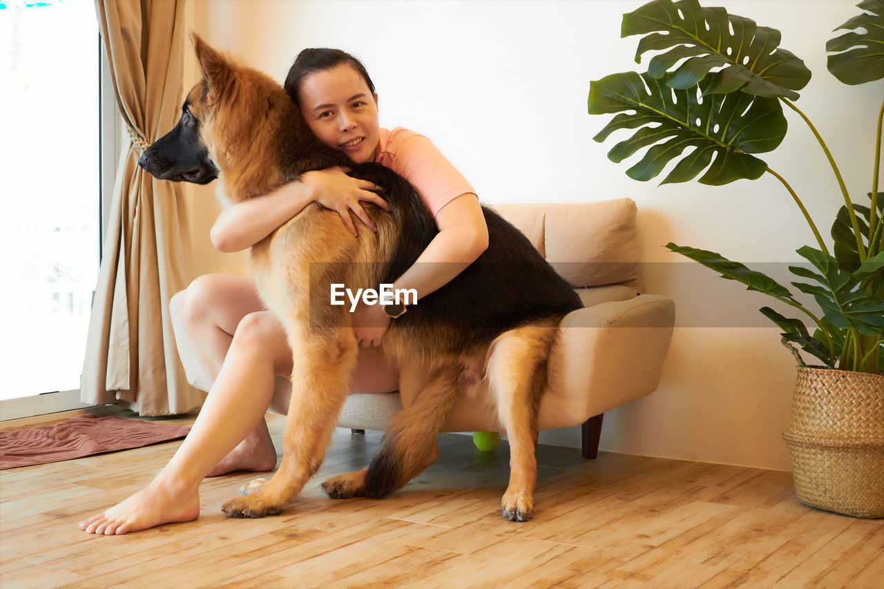 Woman togetherness hugging german shepherd in room