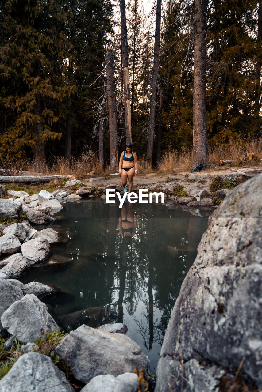 Woman walks into beautiful hot spring with reflection