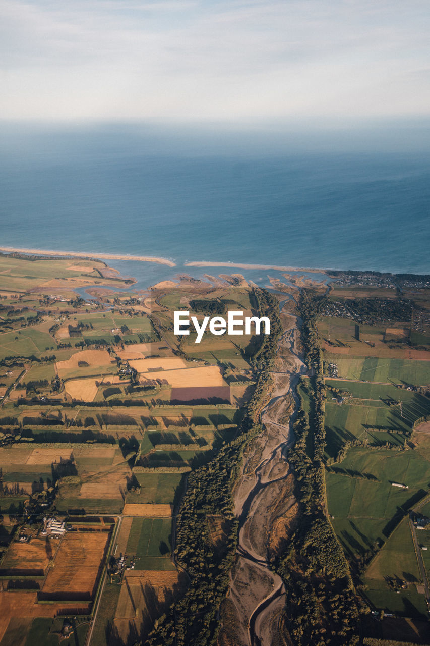 High angle view of agricultural field by sea against sky