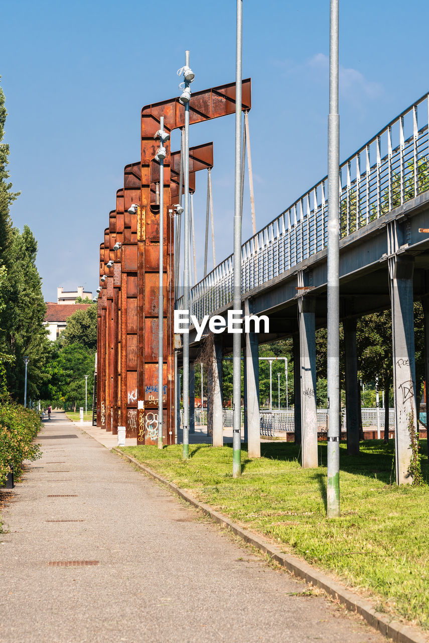 FOOTPATH AMIDST BUILDINGS AGAINST SKY