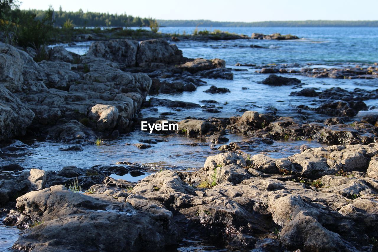 Rocks on sea shore against sky