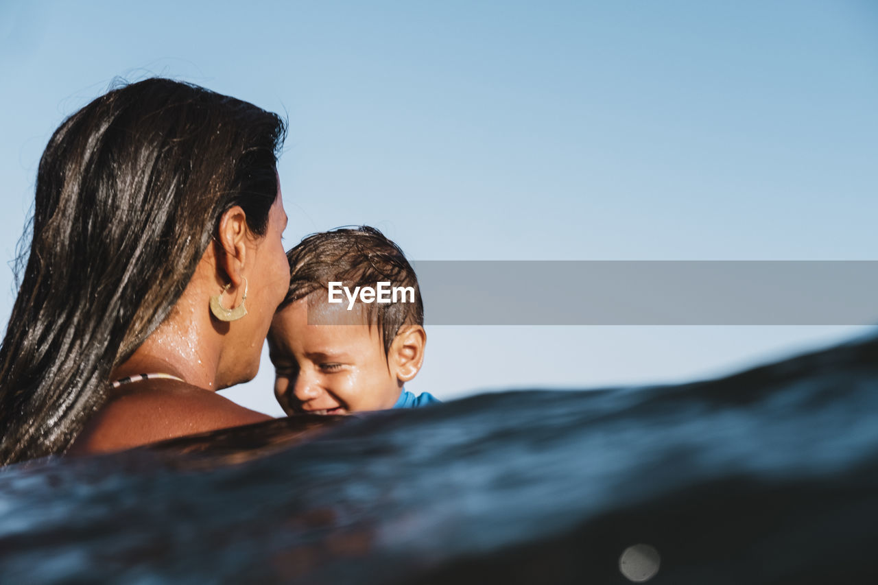 Intimate portrait of mother and son playing at sea