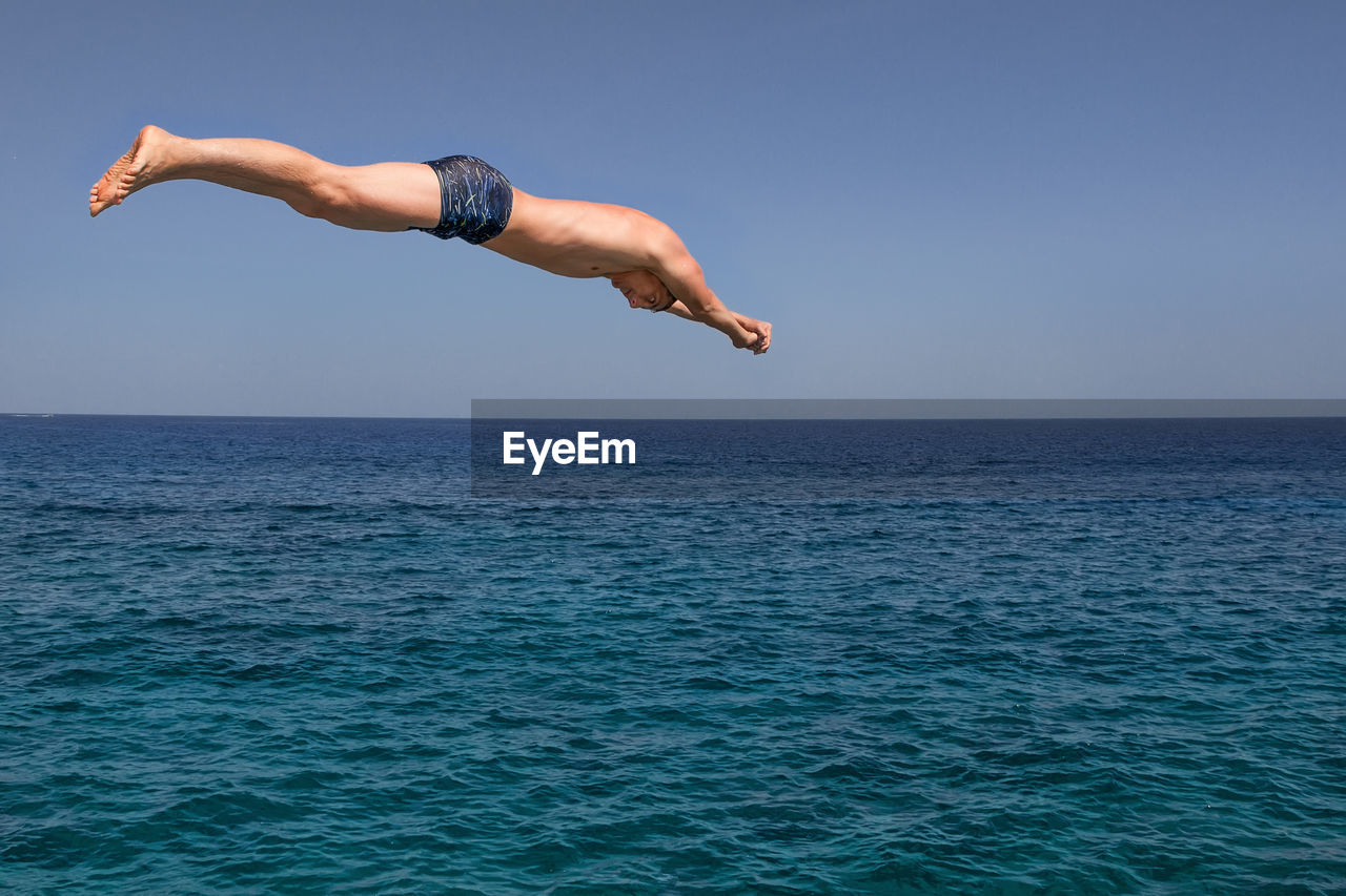 Man jumping in sea against clear sky