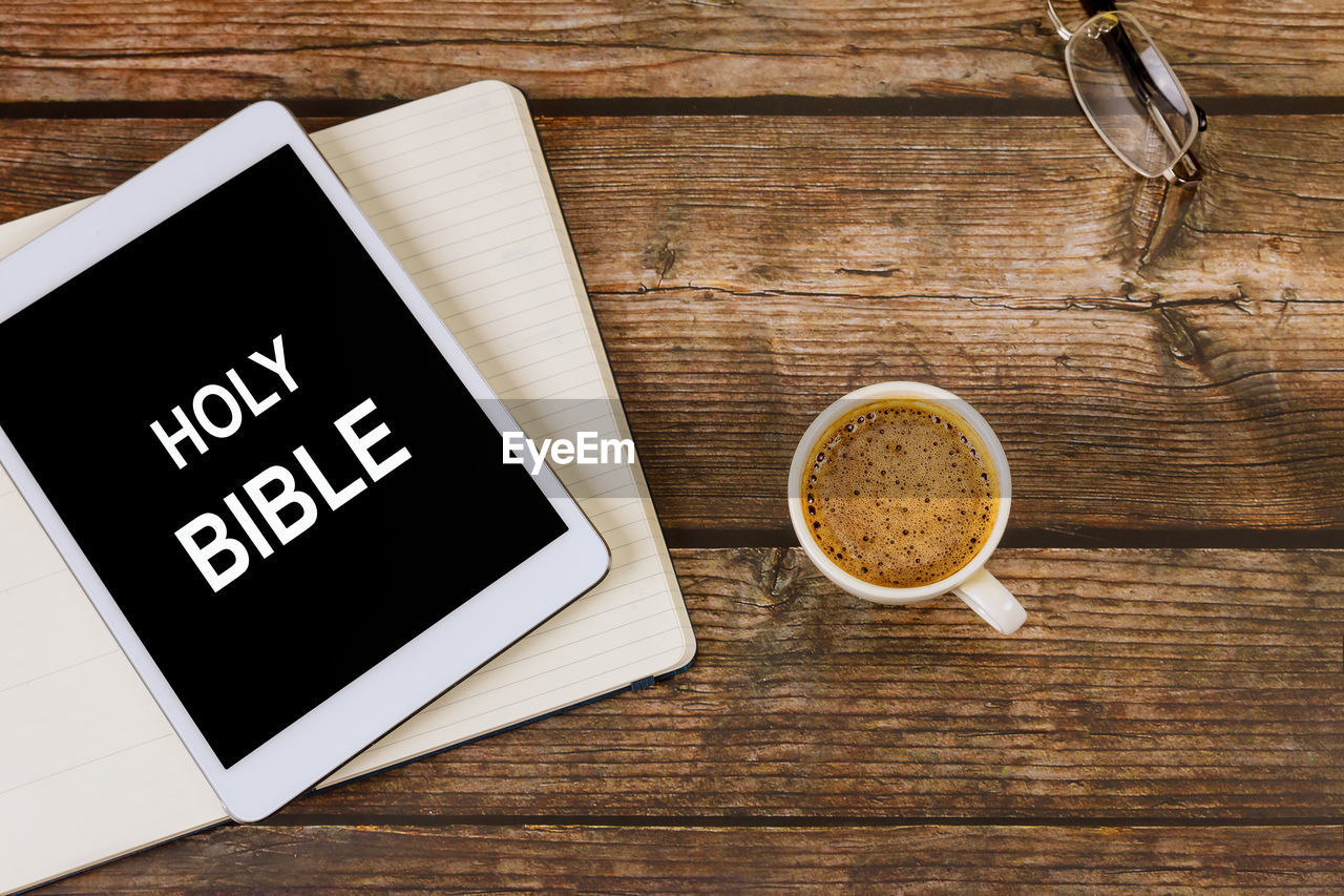 HIGH ANGLE VIEW OF COFFEE CUP WITH TEXT ON TABLE